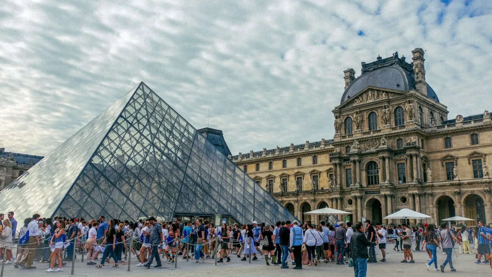 Louvre glass pyramid entrance with visitors